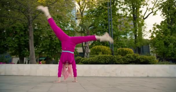 一个穿着粉色衣服 一头粉色头发的快乐女孩在街上表演杂技 快乐的散步和快乐的时刻 — 图库视频影像