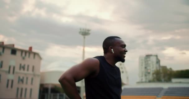 Czarnoskóry Mężczyzna Czarnym Sportowym Mundurze Przechadza Się Stadionie Spogląda Wstecz — Wideo stockowe