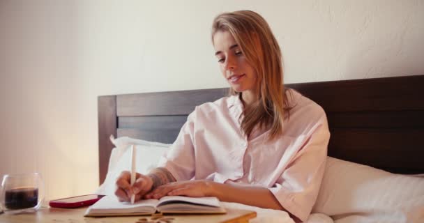 Ein Blondes Mädchen Einem Hellrosafarbenen Nachthemd Schreibt Frühmorgens Mit Einer — Stockvideo