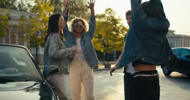 一群年轻时尚的人站在车旁 在阳光灿烂的日子里欢快地跳舞 — 图库视频影像