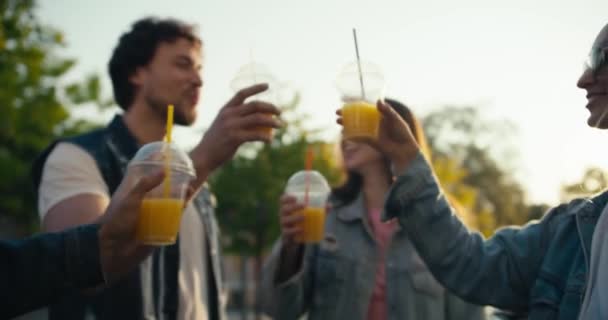 穿着时髦衣服的年轻人站在他们昂贵的汽车旁边 用黄色的鸡尾酒碰杯 城市环境中的幸福生活 — 图库视频影像
