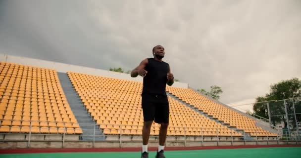 一名身穿黑色运动服 皮肤漆黑的运动员在体育馆里热身 双腿尽量高高地伸展着 — 图库视频影像