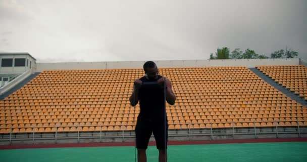 Чернокожий Мужчина Черной Спортивной Форме Белыми Наушниками Используя Специальный Резиновый — стоковое видео