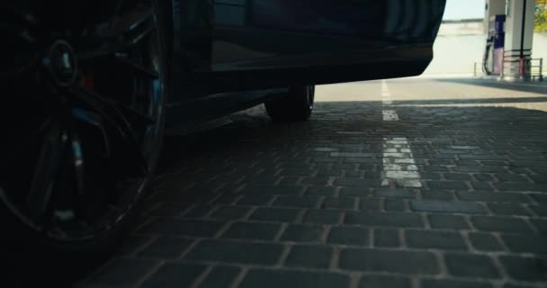 暗い灰色のコンバーチブルから抜け出すとガソリンスタンドで彼の車を埋めるために行く白いスニーカーで男のクローズアップショット — ストック動画