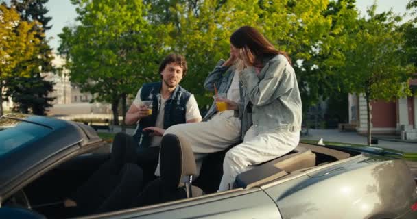 女孩们坐在出租车上 三人组的两个女孩和一个小伙子在卡布列特附近的大街上欢欢喜喜地喝鸡尾酒 聊着天 — 图库视频影像