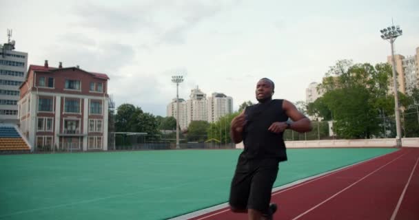 Seorang Pria Berkulit Hitam Dalam Pakaian Olahraga Hitam Menjalankan Perlombaan — Stok Video