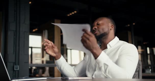 一名身穿白衬衫的黑人男性办公室职员正在翻阅这些文件 并把它们扔到一边 因为它们是不正确的 办公室问题的解决 — 图库视频影像