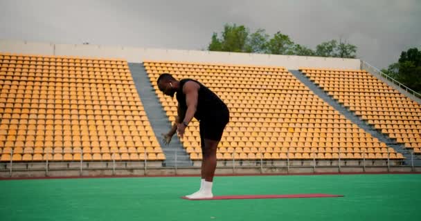 Zwarte Man Zwarte Sportkleding Doet Yoga Een Groen Stadion Met — Stockvideo
