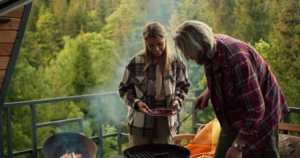 这对夫妇正在休息 并在一座俯瞰森林和高山的乡间房子里野餐 那个男的和那个金发姑娘一起去野餐烧烤 — 图库视频影像