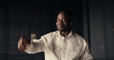 Beyaz tişörtlü başarılı iş adamı, kablosuz kulaklıkla müzik dinliyor ve arka planda dans ediyor. Zafer dansı..