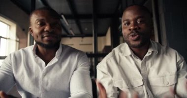 Beyaz gömlekli iki siyahi iş adamının planları ve işleri hakkında duygusal olarak konuştuğu birinci şahıs video konferansı..