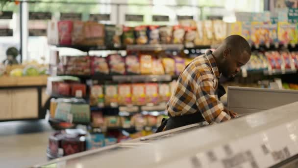 Muž Černou Barvou Pleti Kostkované Košili Třídí Výrobky Ledničce Supermarketu — Stock video