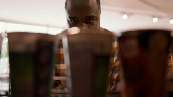 一个黑皮肤男子的特写镜头走到柜台前 拿起中间的一个产品 — 图库视频影像