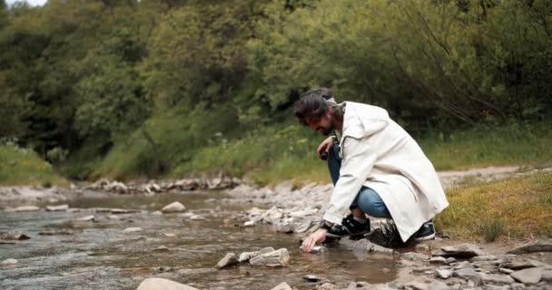 Beyaz Ceketli Bir Adam Ormanda Yürürken Bir Dağ Nehrinden Termosa — Stok video