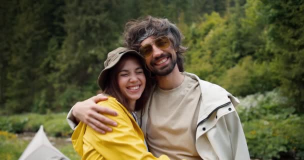 幸せなカップルの肖像画 男と女の子は 緑の森の背景にハイキング服 抱擁と微笑みながら立っている — ストック動画