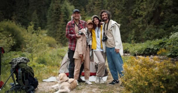 快乐的游客同行 2个男人和2个女孩穿着背包 穿着远足服装 在绿林的背景下 摆出姿势 看着相机 — 图库视频影像