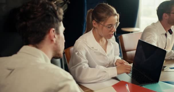 一位穿着白衬衫戴眼镜的金发姑娘用笔记本电脑向一位穿着白衬衫的经理展示了她的计划 — 图库视频影像