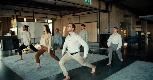 一个穿着白衬衫和眼镜的男人正在和同事们一起做瑜伽 — 图库视频影像