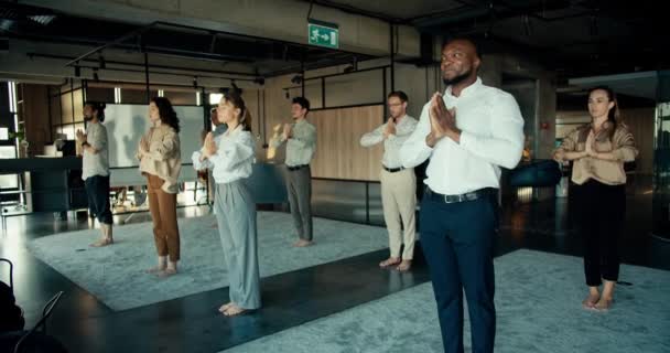 办公室的团队从事冥想和瑜伽 办公室职员站在地毯上 双手交叉放在办公室前面 — 图库视频影像