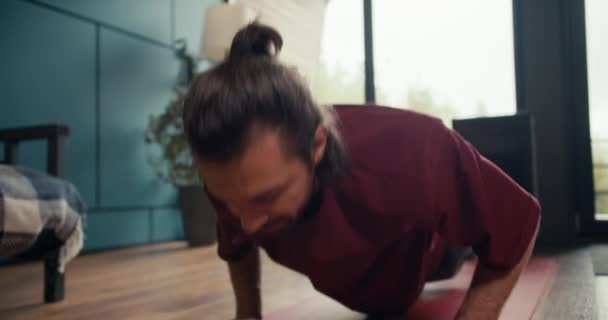 一个穿着红色T恤的快乐的黑发男人在家里做了俯卧撑练习 站起来擦拭额头 家庭健美 — 图库视频影像