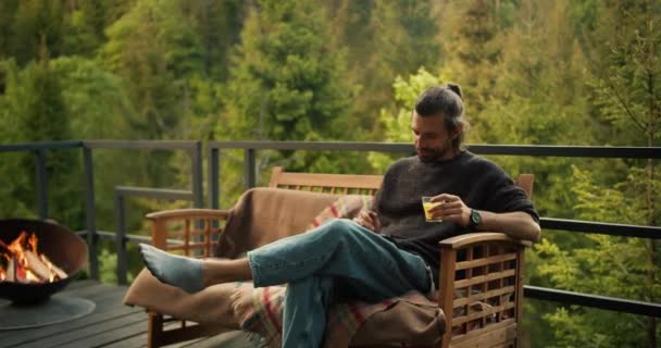 Elinde Sarı Bir Içki Olan Bir Adam Kanepeye Oturur Dağlara — Stok video