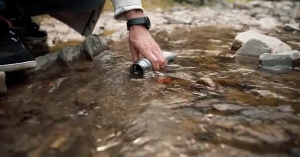特写镜头 一个人在远足时从山河中的热水瓶中取水 — 图库视频影像