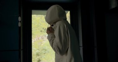 Beyaz ceketli esmer bir adam soğuk dağlarda yürüdükten sonra sıcak bir kır evine girer. Adam dış giysisini çıkarıp eve giriyor..