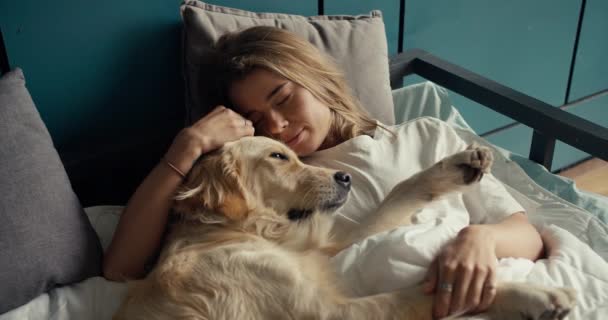 特写镜头 一个金发女孩早上和她浅色的狗睡在床上 快乐的宠物主人 — 图库视频影像