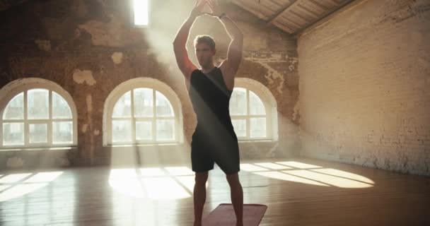 镜头对准了一个身穿黑色运动服的男人 他在阳光灿烂的大厅里伸展着胳膊和肩膀 训练前练习及热身 — 图库视频影像