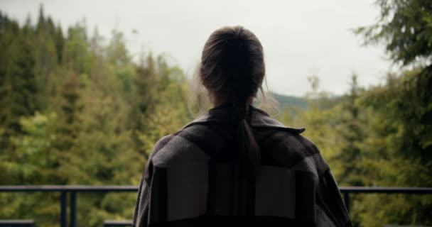 一个快乐的金发姑娘 拿着一杯咖啡 走到一座乡间别墅的阳台上 望着山上郁郁葱葱的针叶林 — 图库视频影像