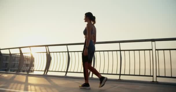 Seorang Gadis Atletik Muda Dalam Pakaian Olahraga Berjalan Sepanjang Jembatan — Stok Video