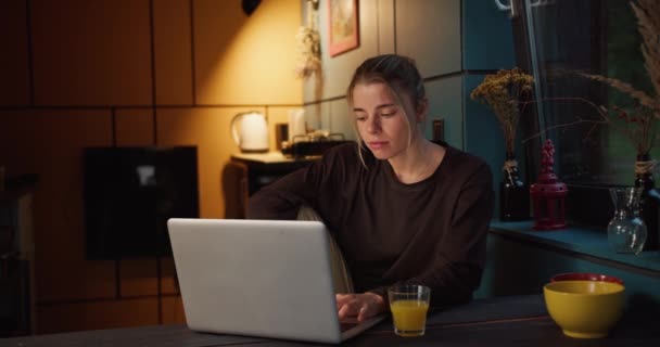 一个快乐的金发碧眼的女孩在昏暗的黄昏房间里 看着一台白色笔记本电脑的屏幕上闪烁着一盏黄色的灯 高兴极了 — 图库视频影像