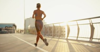 Spor yaz üniformalı, sabahları koşan genç bir kızın arka görüntüsü. gündoğumu güneş ışığı.