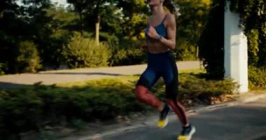 Spor yaz üniformalı bir kız sabah parkında hızla koşuyor. Sağlığınızı ve vücudunuzu geliştirmek için spor ve koşuşturma.
