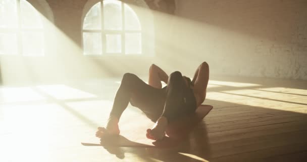 一名身穿黑色运动夏装的男子参加体育运动 并在阳光灿烂的砖楼里做抽吸腹部肌肉的运动 — 图库视频影像
