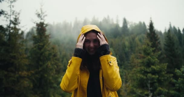 Счастливая Девушка Жёлтой Куртке Стоит Фоне Хвойного Горного Леса Надевает — стоковое видео