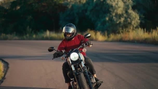 一个穿着红色毛衣 头戴摩托车头盔的男人在阳光灿烂的天气有效地在路上转弯 骑摩托车是一种业余爱好 — 图库视频影像