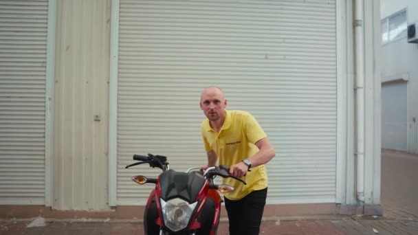 Egy Kopasz Férfi Sárga Pólóban Vezet Egy Piros Mopedet Garázsba — Stock videók