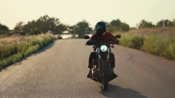 赤いジャケットとヘルメットのオートバイのバイクは 風で晴れた天気の道路に乗っています — ストック動画