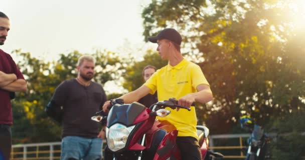 一位穿着黄色T恤的驾驶教练教他的学生如何坐在摩托车上 如何正确驾驶摩托车 天气晴朗时在一所摩托车学校的场地授课 — 图库视频影像