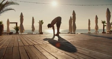 Yogi 'li adam, tuzlu sahildeki yoga dersi sırasında ellerini kaldırıyor. Yoga ve zen stili.