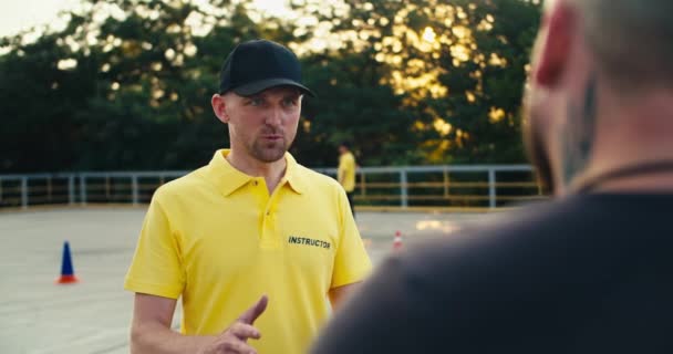 Muž Instruktor Žlutém Tričku Čepici Komunikuje Studentem Řízení Motocyklu Cvičišti — Stock video