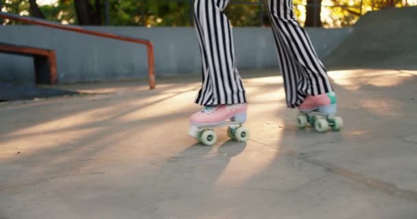 一个女孩穿着紫色上衣和条纹裤子 骑着粉色轮滑冰鞋在室外滑板上短发的画像 — 图库视频影像