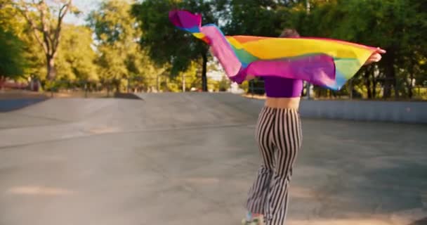 스케이트 공원에서 보라색 상단과 줄무늬 블레이드와 흔들리는 Lgbt 깃발을 소녀의 — 비디오