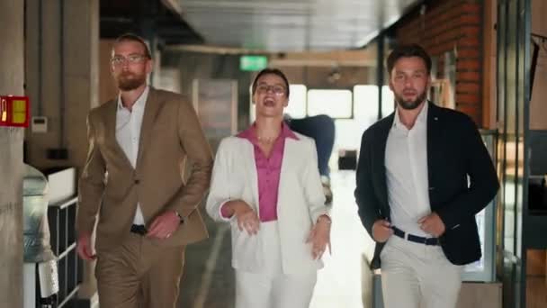 ハッピー3オフィスワーカー ラウンドメガネのブルネットガールとピンクのシャツの白いジャケットは オフィスやダンスの彼女の同僚や男性と歩きます — ストック動画
