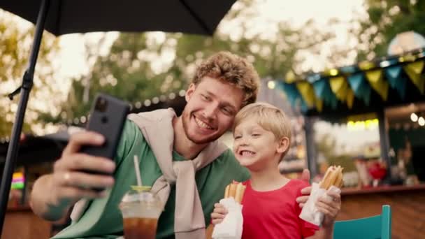 Kıvırcık Saçlı Yeşil Tişörtlü Mutlu Baba Elinde Iki Sosisli Sandviçi — Stok video