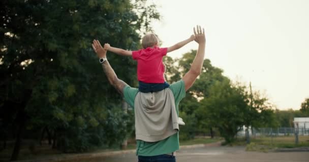 Visão Traseira Menino Louro Sentado Seus Pais Ombros Uma Camiseta — Vídeo de Stock