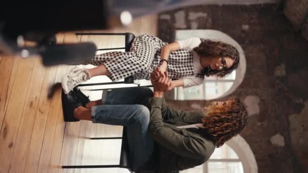 垂直ビデオ カーリーヘアを着用しているブルネットの少女と茶色のカーリーヘアを持つ男が一緒にコミュニケーションし グループ療法中に手を握る — ストック動画