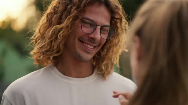 一个穿着白衬衫戴眼镜的快乐的卷发男人正在和他的女朋友说话 — 图库视频影像