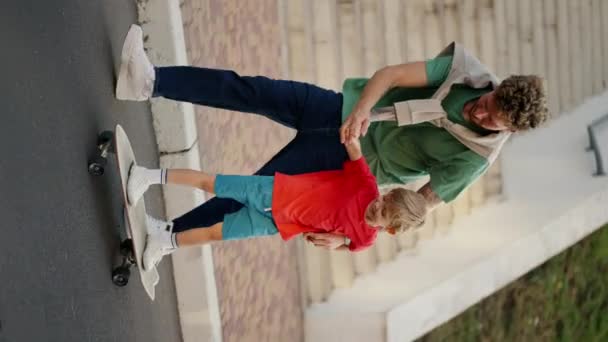 티셔츠와 청바지 빨간색 티셔츠와 반바지 공원에서 도로를 스케이트 보드를 아들을 — 비디오